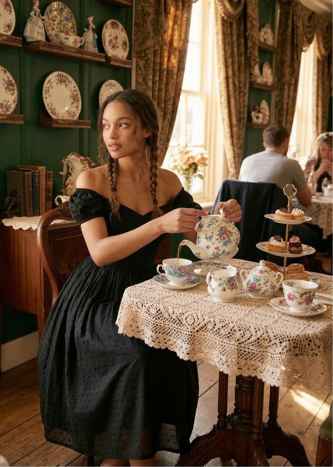 Woman in a black dress sitting at a table with a teacup in a decorated room.