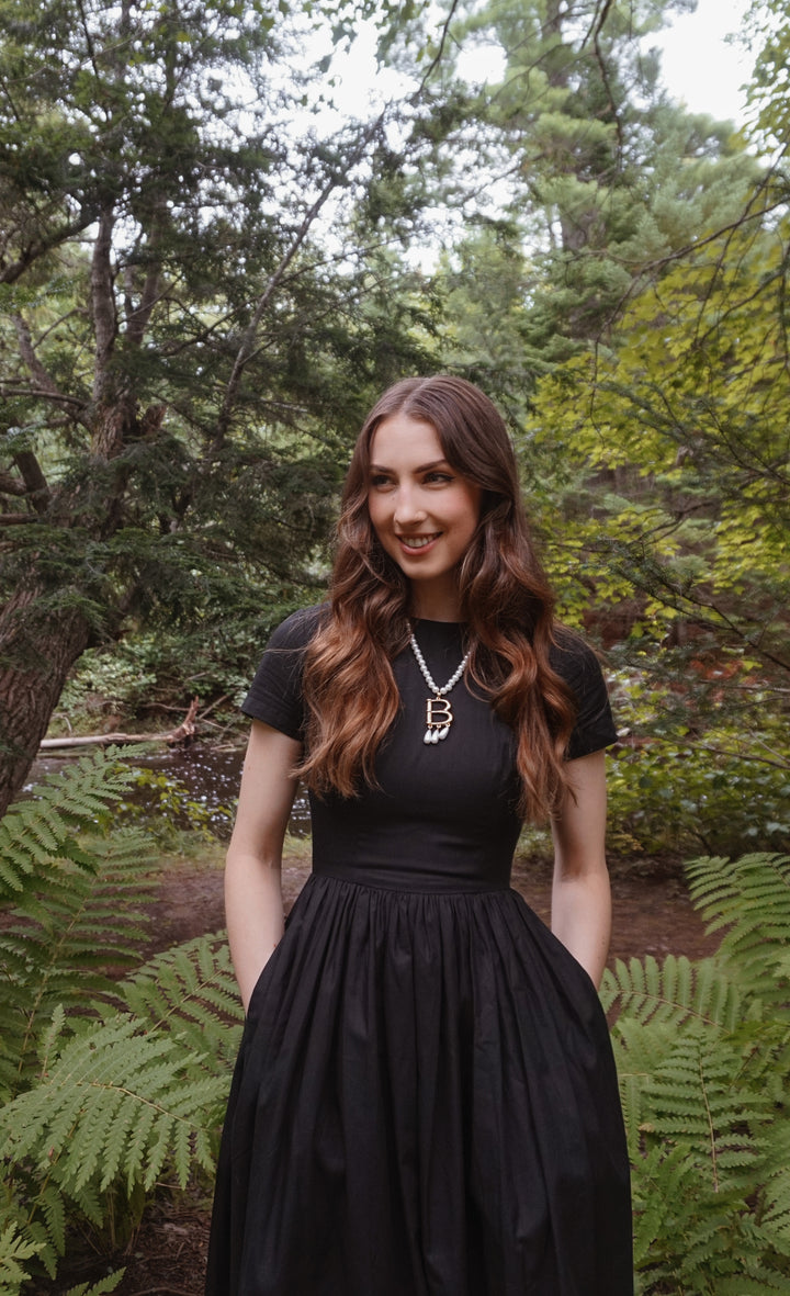 Woman in a black dress standing in a forest