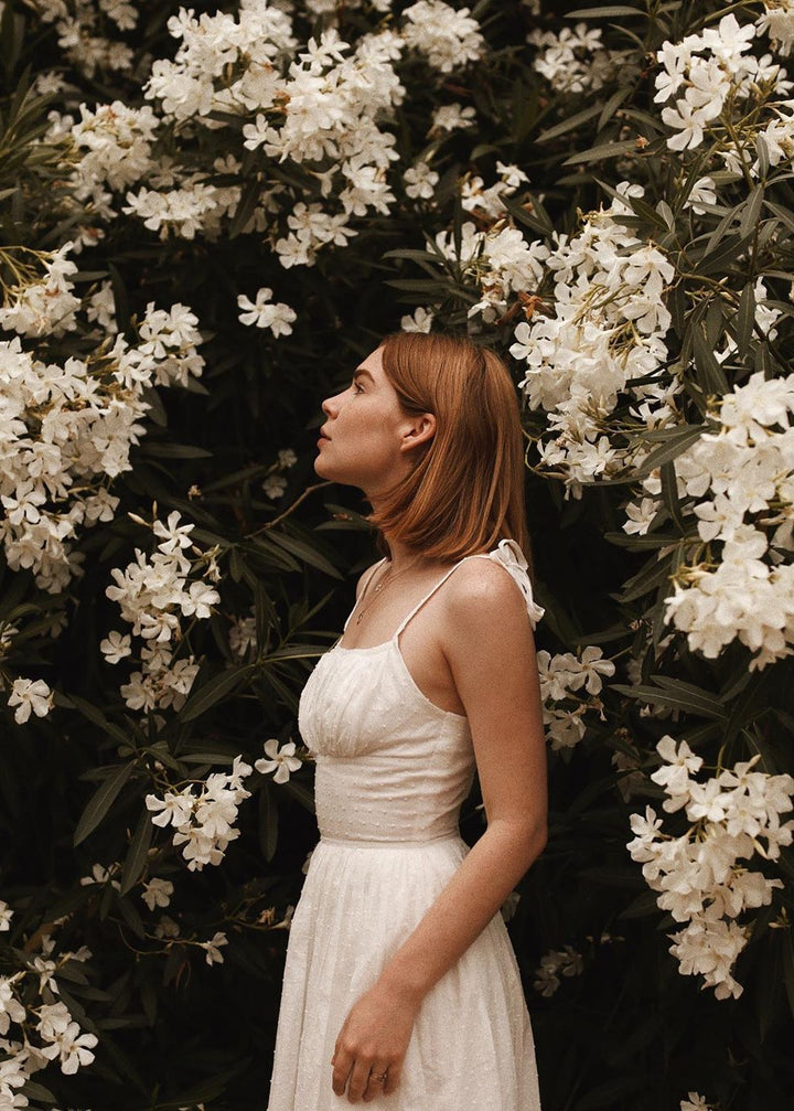 Woman in a white dress standing among white flowers