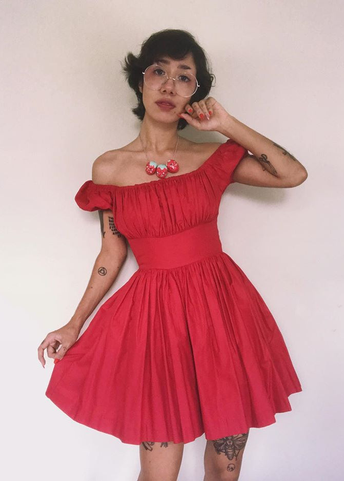 Person wearing a red off-shoulder dress against a plain background